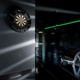 Dartboard on a wall with a dark room and green light in the background Dartboard on a wall with a dark room and green light in the background
