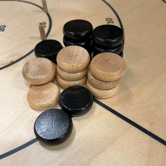 Wooden crokinole men in natural and black colors on a crokinole board
