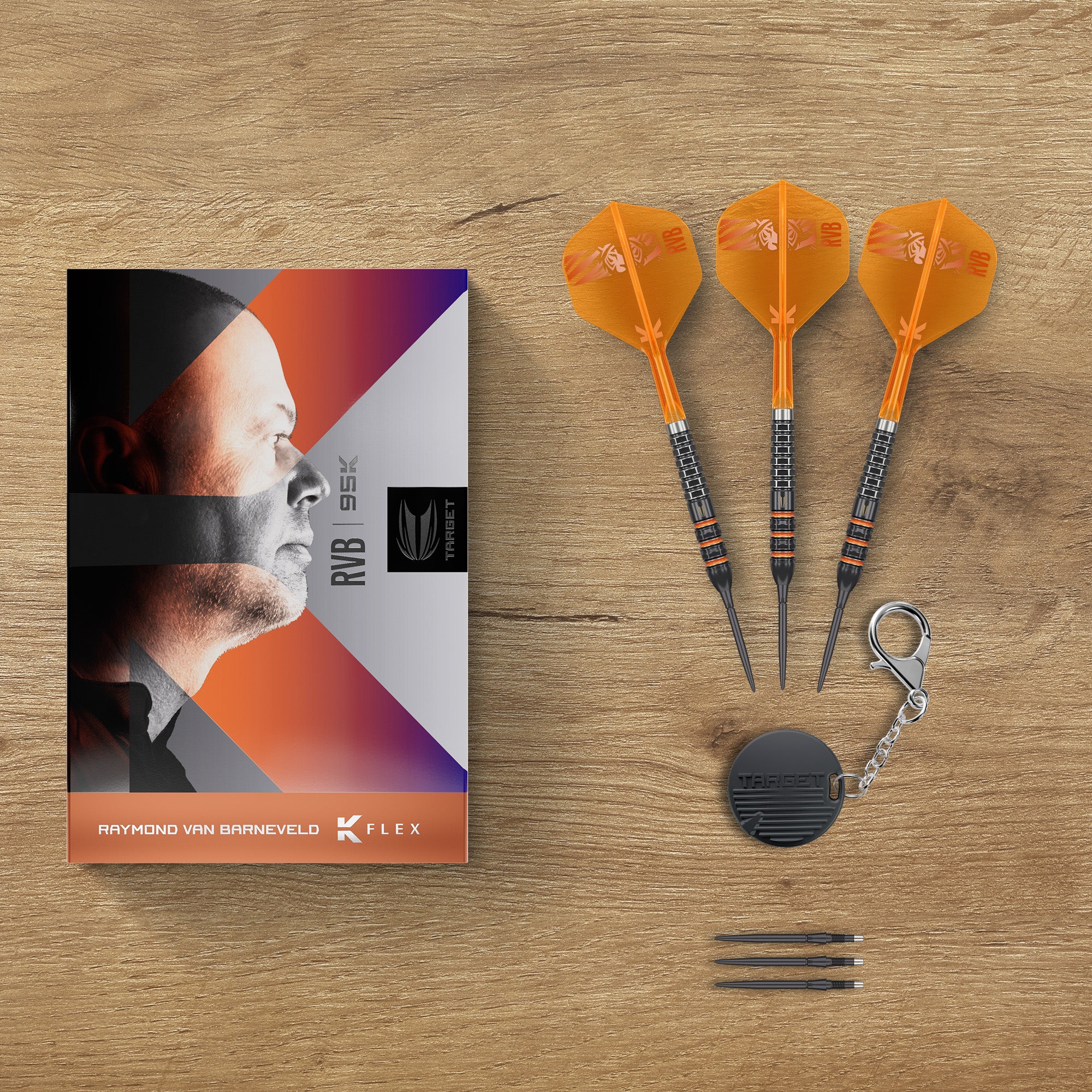 Raymond Van Barneveld 95K SP 95% Tungsten, a black round swiss tool, three darts, and a branded retail box on a light brown wooden background.