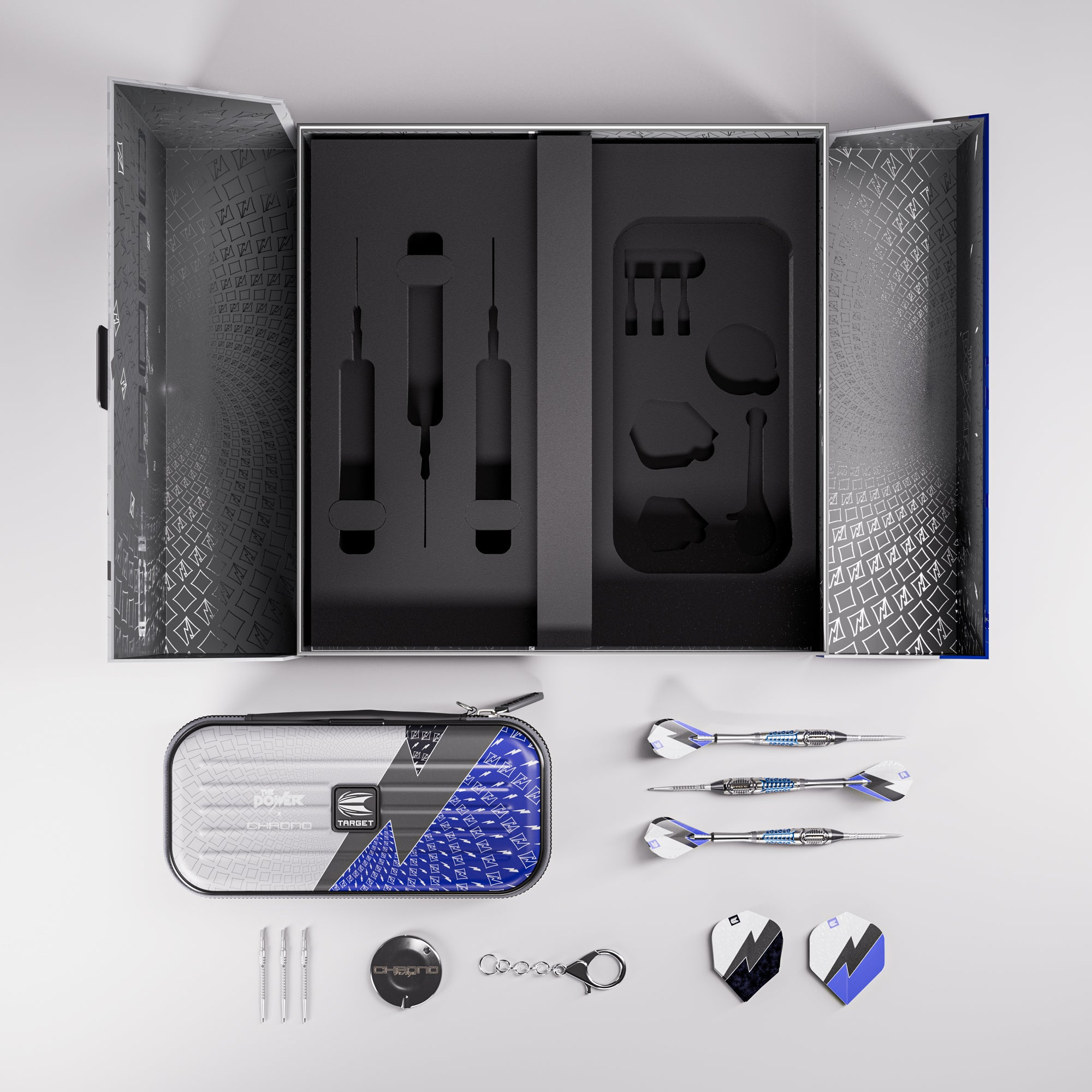 A professional dart set arranged in a top-down layout on a light gray background. The set includes a large black presentation box with custom foam inserts, a silver and blue patterned zippered carrying case, three darts, three tips, a black dartboard cover, a black keychain, and several small accessories.
