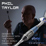 A promotional product image for a dart shaft featuring Phil Taylor, the 16x World Champion. The dart shaft, branded 'The Power x Chrono', is shown diagonally in the foreground with blue and white flight bits, while Phil Taylor holds a dart in his hand in the background.