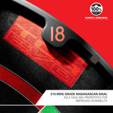 A close-up of a black curved ring with a number 18 on it, placed over a red and black textured surface. A white label at the bottom reads '215-MDG GRADE MADAGASCAN SISAL SELF-HEALING PROPERTIES FOR IMPROVED DURABILITY,' and a circular '100% SHE-MDG GRADE MADAGASCAN SISAL' seal appears in the top right.